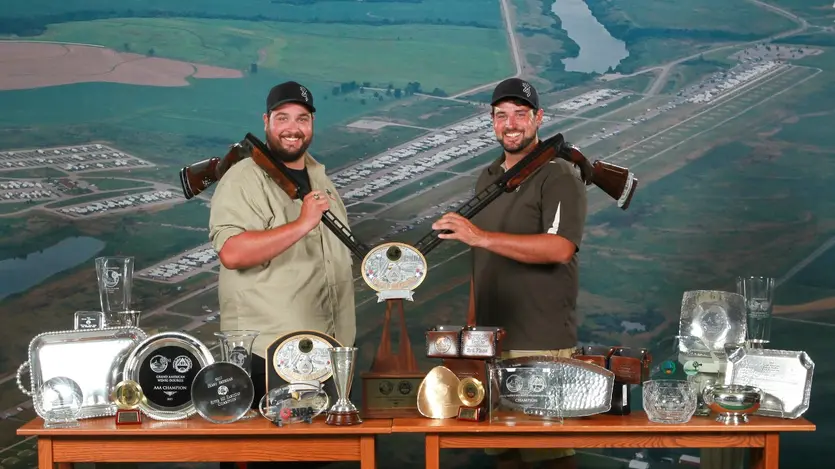 Matt and Foster posing with dozens of trophies